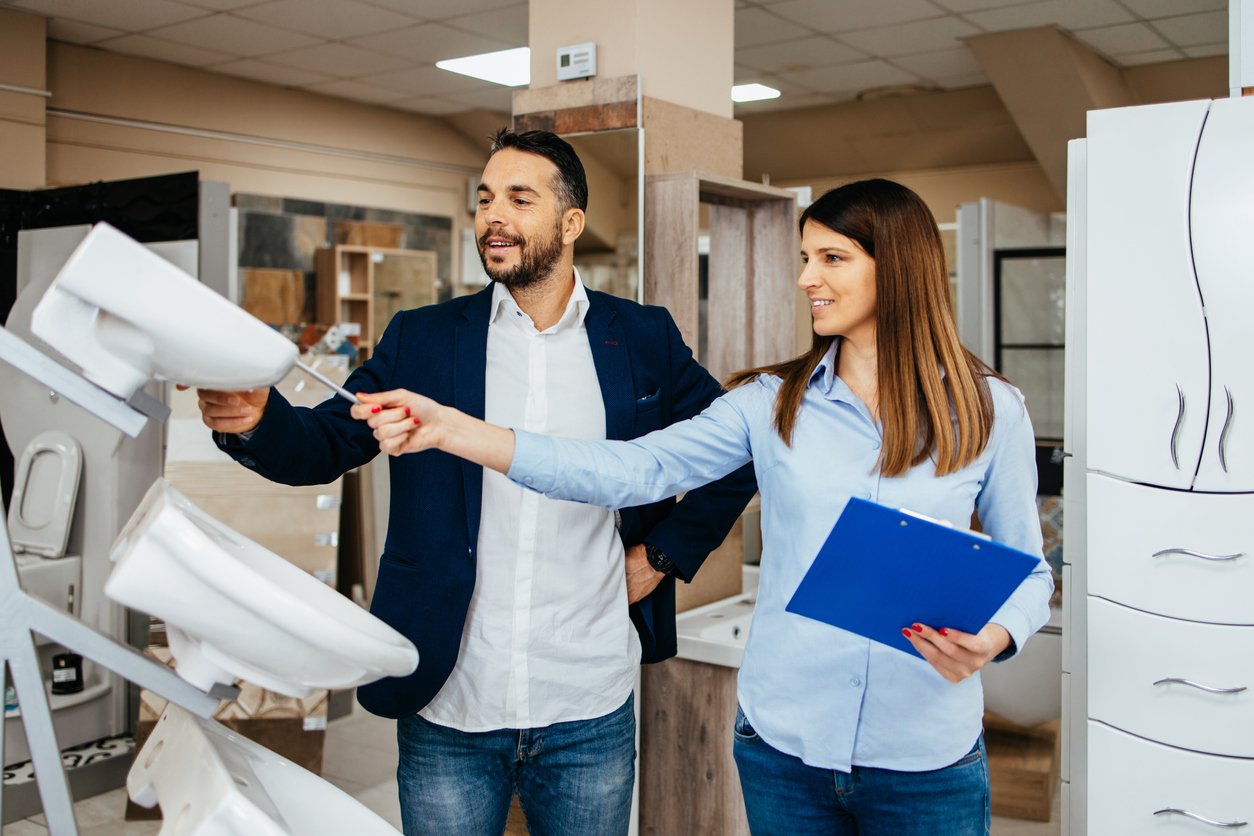 Couple shopping for plumbing fixtures debating over an elongated vs. round toilet