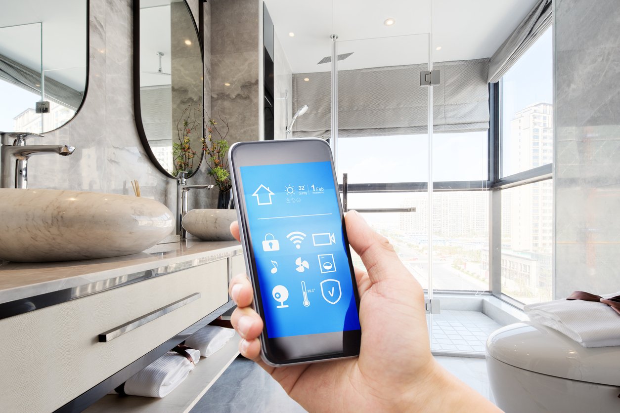 hand holding a smartphone standing in the bathroom using their device to program fixtures in their smart bathroom